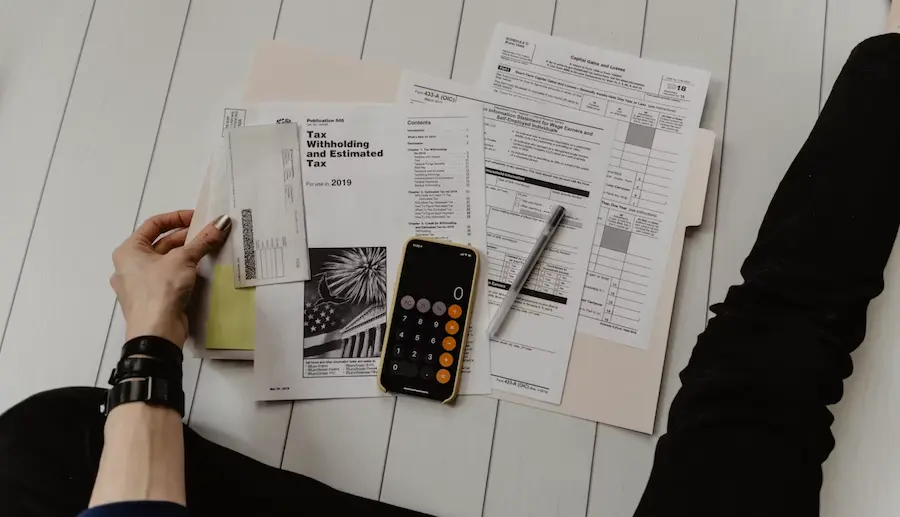 "A person reviewing financial documents and using a smartphone calculator to assess expenses, representing the concept of financial planning and income protection."