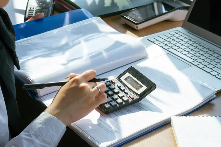 Self-employed professional calculating solo 401k contribution limits at a home office desk with calculator, laptop, and financial documents