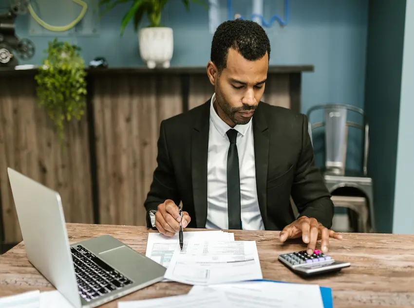Homeowner reviewing loan documents and financial statements at kitchen table with calculator