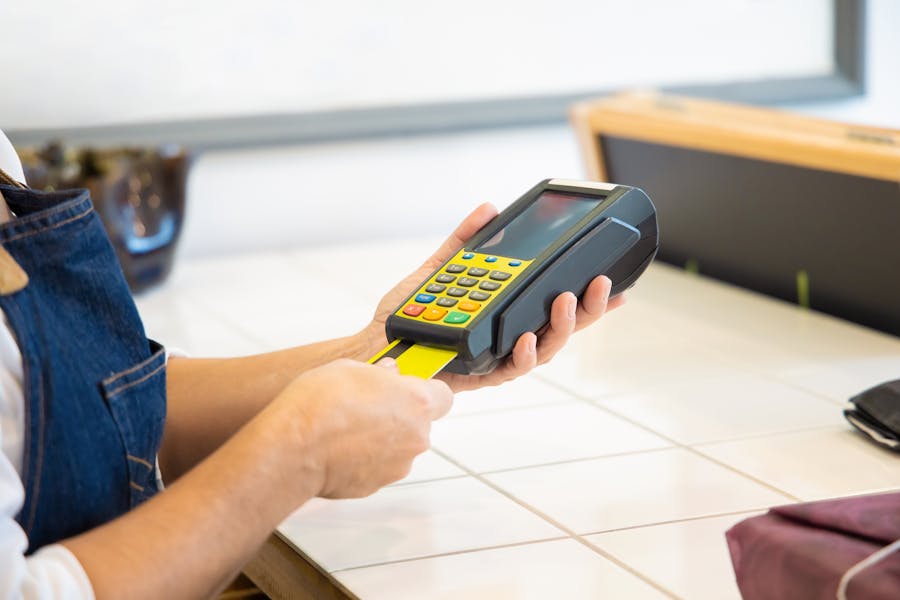 Cashier swiping a card in a POS terminal, demonstrating credit card processing for small business.