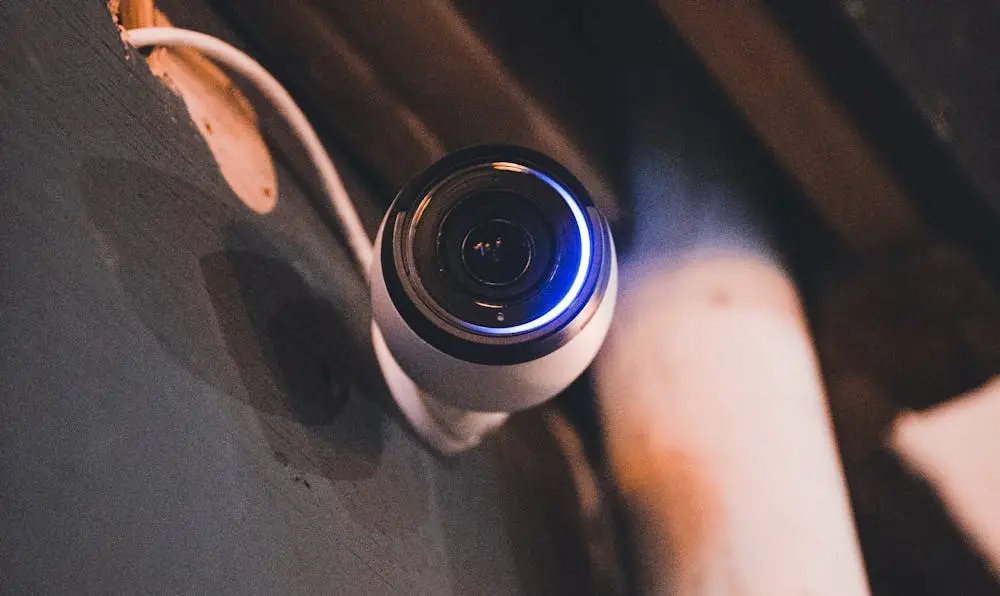 A modern dome-style smart home security camera with a glowing blue LED ring, representing the best smart home security systems in 2026.