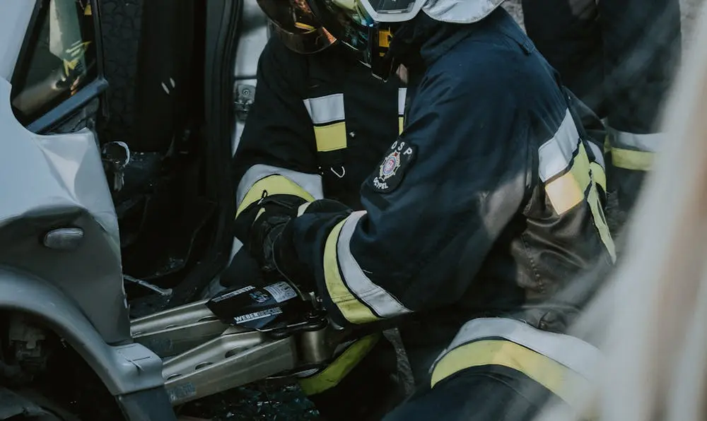 Emergency rescue personnel using heavy extraction tools on a severely damaged car after a major collision, representing the complex aftermath of personal injury claims.