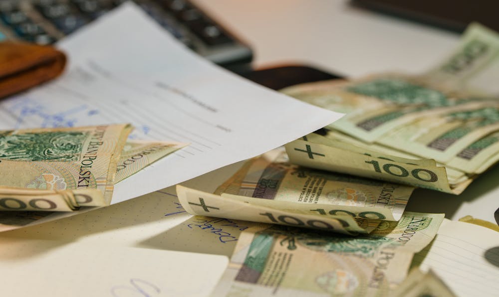 "Banknotes scattered over financial documents, representing the money-saving benefits and cost analysis of working with local car insurance agents."