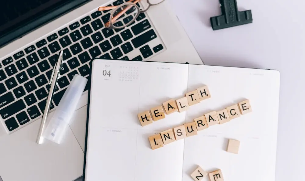 "Wooden letter blocks spelling Health Insurance on a notebook, representing health insurance planning for tourists in the USA."