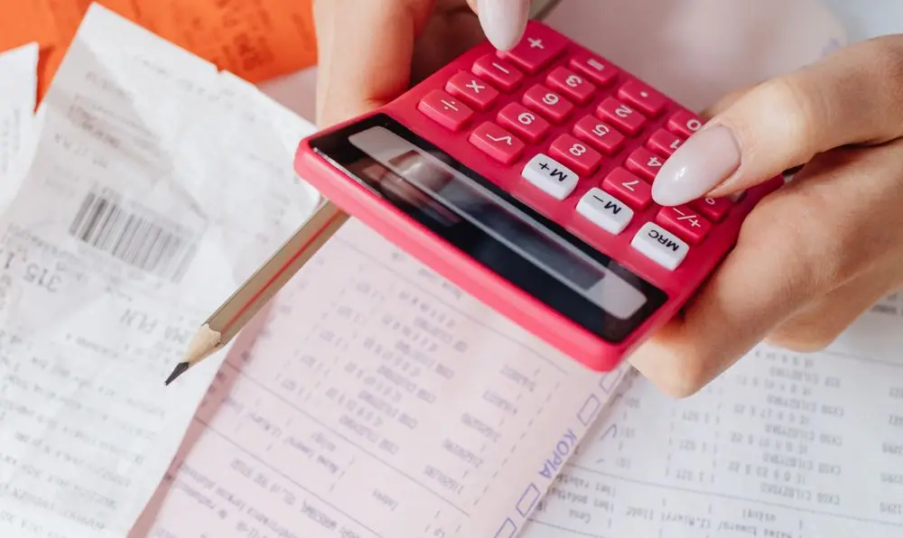 "Close-up of hands using a red calculator to manage medical bills and calculate Medicare Advantage plan costs."
