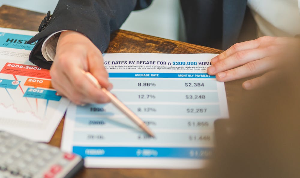 A person using a pen and calculator to compare interest rates and monthly payments on a financial chart, illustrating how to find the best personal loan interest rates.