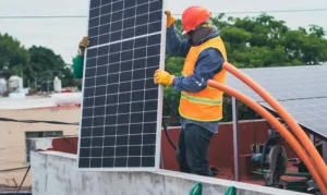 Professional solar installers lifting a new panel onto a residential roof, representing the upfront solar panel cost and installation process for 2026.