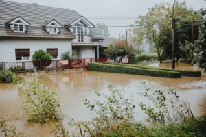 A residential home surrounded by severe muddy floodwaters, illustrating the critical need for property protection and evaluating policies like Wright flood insurance.