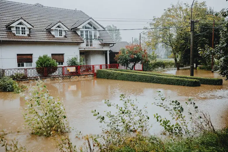 A residential home surrounded by severe muddy floodwaters, illustrating the critical need for property protection and evaluating policies like Wright flood insurance.