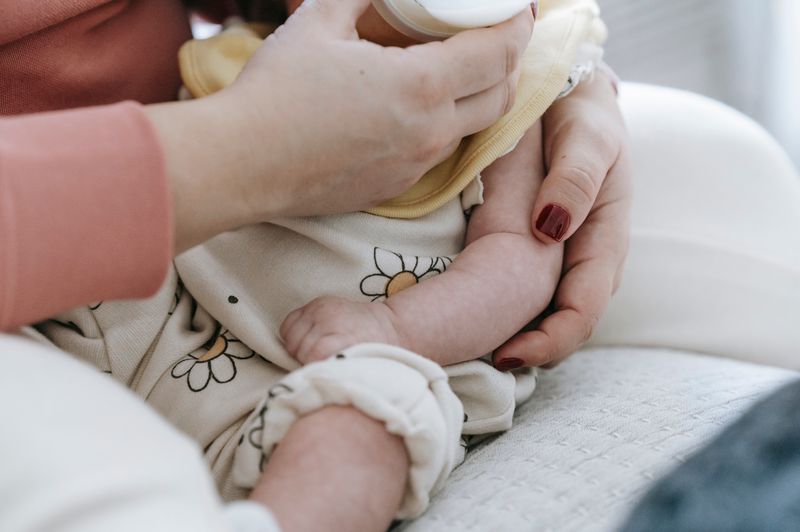 A caregiver feeding an infant with a baby bottle, representing early childhood nutrition and infant health concerns discussed in the 2026 NEC lawsuit context.