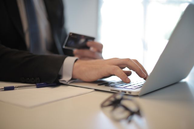"A businessman entering credit card details on a laptop for an online transaction."