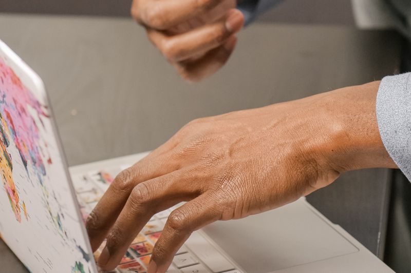 Close-up of a person's hands typing on a laptop keyboard, illustrating a consumer carefully researching and comparing no-fee balance transfer credit card offers online.