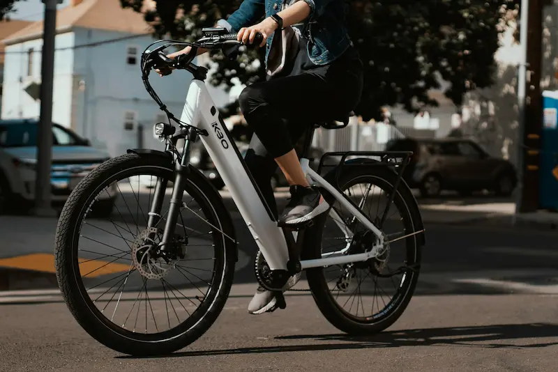 A commuter riding a high-value white electric bike on a city street, illustrating the need for proper renters insurance e-bike coverage against theft.