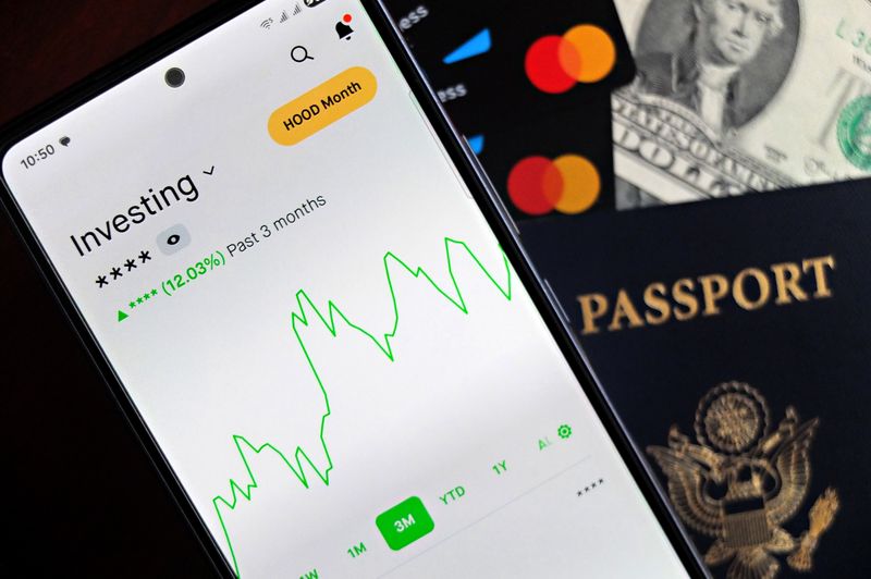 "A smartphone displaying a green stock market investment chart next to credit cards, a US passport, and dollar bills, representing dividend investing and financial freedom."
