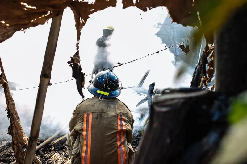 "A firefighter in protective gear and a blue helmet watching a smoky fire, representing the occupational hazards and potential AFFF foam exposure related to ongoing lawsuits."