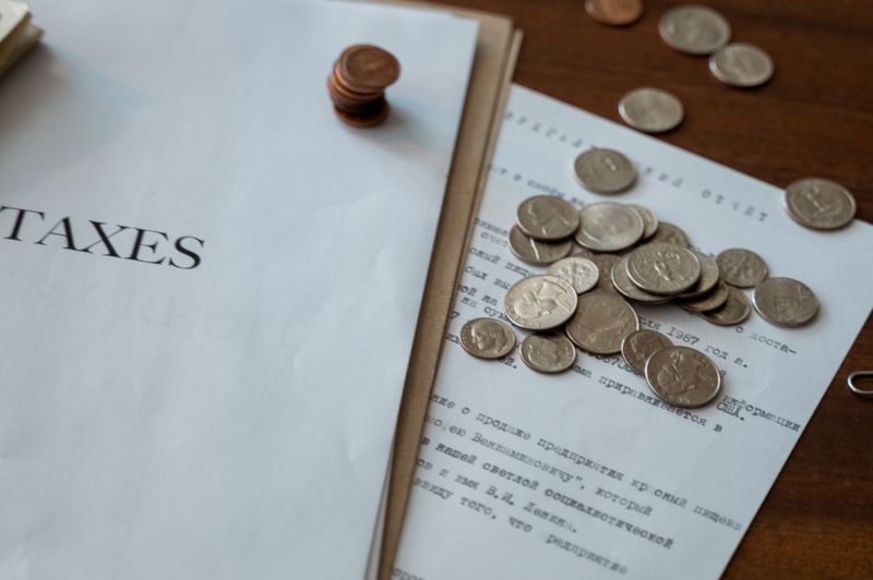"Close-up of a 'TAXES' document with vintage coins scattered over financial papers, symbolizing RMD calculations and tax obligations."