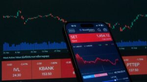 A smartphone screen displaying the StockRadars app with real-time stock charts and declining market indices, set against a dark background of active financial trading screens, illustrating after-hours stock trading activity.