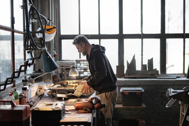 A focused small business owner working with tools in a well-equipped workshop, representing entrepreneurship, skilled labor, and operational risks covered by commercial insurance.