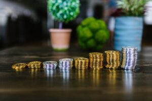 Stacks of gold and silver coins increasing in size on a wooden table, symbolizing the power of compound interest and wealth growth.