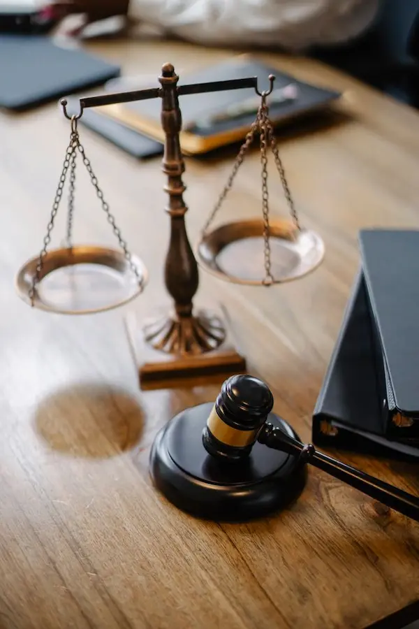 A legal-themed desktop featuring a classic brass scale of justice and a wooden judge’s gavel resting on a polished wooden table alongside law books, illustrating the legal framework and timelines behind the statute of limitations on debt.