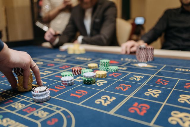 A blue roulette table in a casino with colorful betting chips on numbers, representing gambling wagers and financial gains or losses.